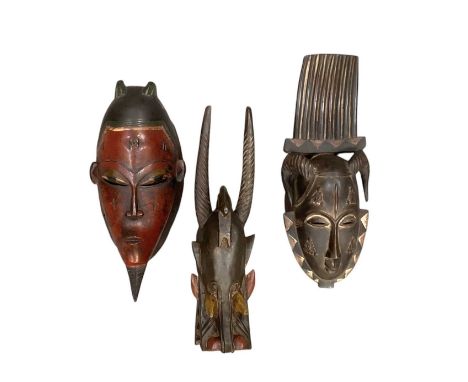 Three African carved wooden masks including Yaure Senufo fire spitter mask, height 44cm, comb mask, height 41cm, and a red pa