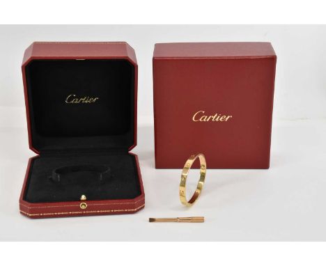 CARTIER; an 18ct gold hinged LOVE bracelet with screw motifs, marked to the inside 'Cartier 17 AZZ732 Au750' and with various