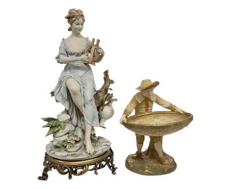 An early 20th century Contintental porcelain figure depicting a girl playing a lyre in a garden setting, raised on a metal ba