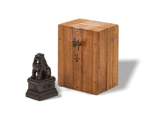 Ca. AD 1800 - 1900. A netsuke finely carved from ebony as a seated karashishi (Buddhist lion-dog) on a square plinth base, it