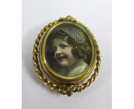 Gilt metal locket brooch / pendant, the glazed panel containing a photographic print of a young girl, 6cm 