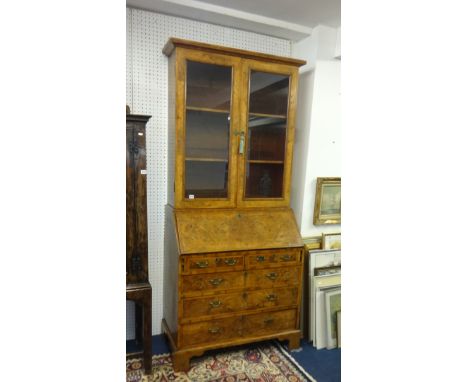 An antique English walnut bureau bookcase the upper section with two glazed doors, enclosing two shelves, the base with a fal