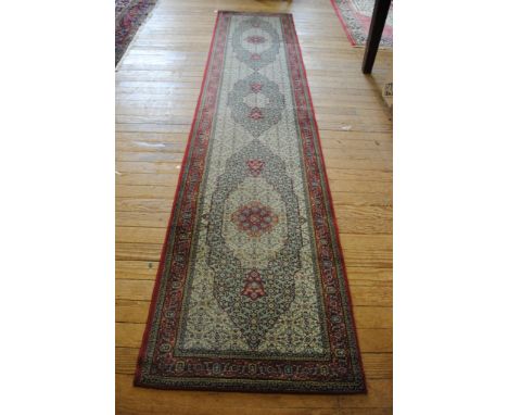 A Middle-Eastern style red ground floor runner with twin border, 305cm x 76cm
