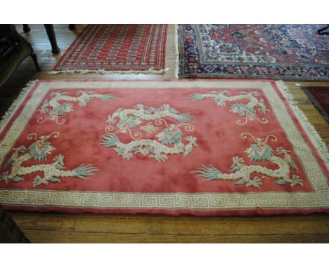 A pink-ground 'Jade' super washed Chinese wool rug depicting five dragons with Greek-key border and long fringe, 250cm x 150c
