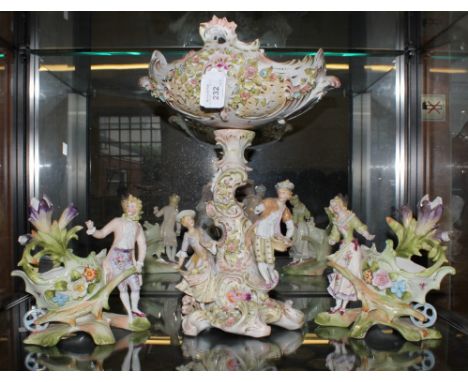 A 19th century Meissen-style ceramic table centre, raised on a stylized figurines and base with a pair of similarly decorated