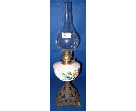 Early 20th century brass single burner oil lamp with ceramic floral painted reservoir on a pierced metal base, having clear g