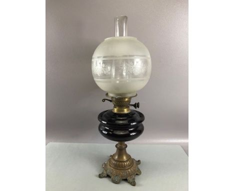 Oil lamp with deep purple central reservoir and etched glass shade and chimney on a brass bass overall approx 55cm tall 