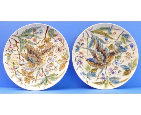 A pair of 19th century continental pottery chargers; decorated in majolica glazes in relief with two open-winged birds amongs