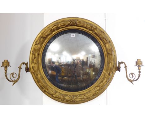 A large early 19th century circular gilt framed convex looking glass; the frame as a laurel leaf wreath centred at the top wi