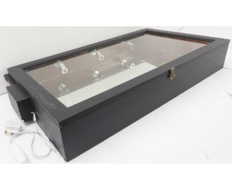 An ebonized framed table display cabinet with angular glazed lid, interior lighting and mirrored base (the frame 87.5cm wide 