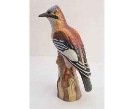 A late 19th / early 20th century German porcelain shaped model of a blue jay perched upon a tree trunk (3cm firing crack and 