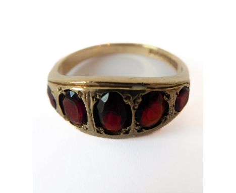 A 9-carat yellow gold garnet-set ring, the five graduated garnets gypsy-set with the engraved mount, Birmingham hallmark, siz