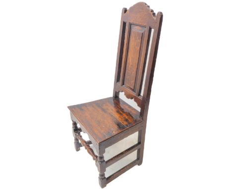 An early 18th century oak side chair; the arched and angular top rail (some historic woodworm) above a single vertical, centr