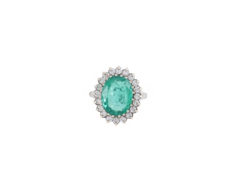 A DIAMOND AND EMERALD CLUSTER RING  The oval cut emerald estimated to weigh 4.20 carats, claw set within a surround of brilli