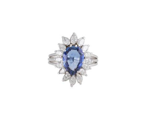 A SAPPHIRE AND DIAMOND CLUSTER RING  The pear cut sapphire estimated to weigh 3.17 carats claw set within a surround of marqu