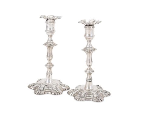 A PAIR OF GEORGE II CAST SILVER CANDLESTICKS JOHN CAFE, LONDON 1756 With shaped circular and shell sconces, reel capitals, kn