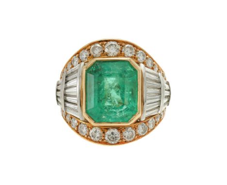 AN EMERALD AND DIAMOND CLUSTER DRESS RING  The step cut emerald with canted corners estimated to weigh 7.15 carats, with tape