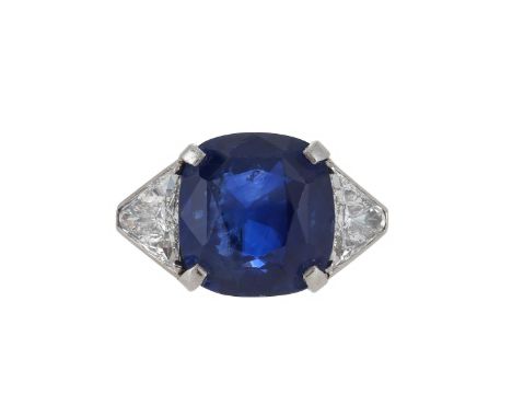 A SAPPHIRE AND DIAMOND THREE STONE RING   The squared cushion cut sapphire estimated to weigh 10.93 carats, flanked by two tr