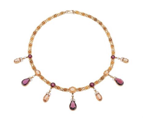 A LATE 19TH CENTURY GOLD, GARNET, TOPAZ AND WHITE ENAMEL FRINGE NECKLACE ATTRIBUTED TO ALFRED PHILLIPS  CIRCA 1890  The neckl