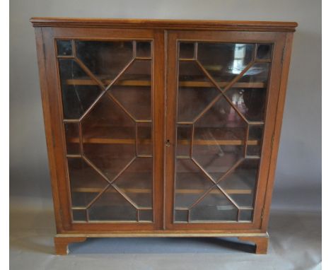 A Mahogany Dwarf Bookcase, the moulded top above two astragal glazed doors enclosing shelves raised upon bracket feet, 109 cm