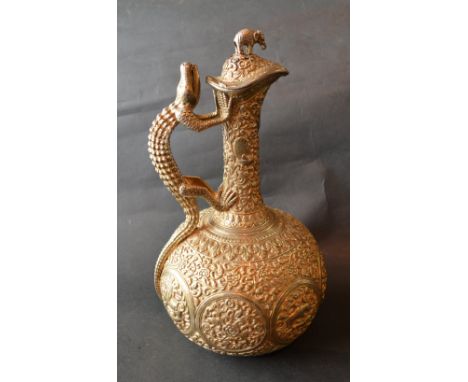 An Indian White Metal and Gilded Jug, the handle in the form of a lizard and with elephant finial, 30 ozs., 27 cms tall