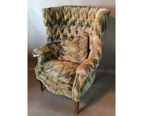 A 19th Century Porters Armchair with a button upholstered back above shaped arms raised upon square tapering legs