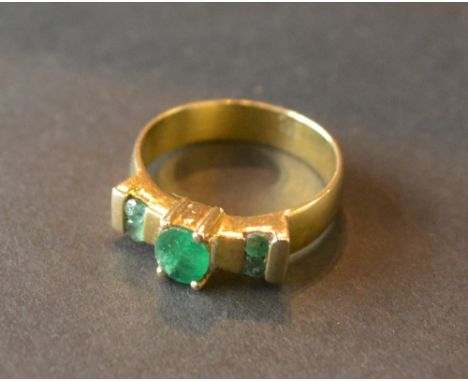 A 14ct. Gold Emerald Three Stone Ring with a central oval emerald flanked by four emeralds