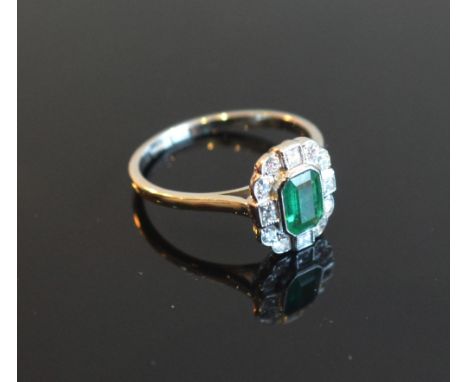 An 18ct. White Gold Emerald and Diamond Ring with a central emerald surrounded by diamonds within a pierced setting