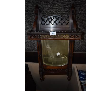 A Victorian gothic style wall mounted mirror having fretwork shelf
