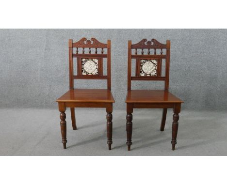 A pair of Victorian walnut Aesthetic movement hall chairs, the back set with a single tile, possibly Minton, with spindle det