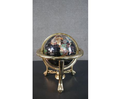 A specimen stone terrestrial desk globe, on a black ground, with a brass frame, on scrolling legs, with pierced stretchers, c