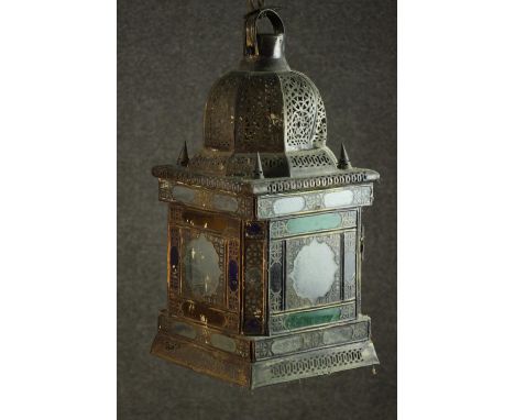 An early 20th century Moroccan brass lantern, the domed top pierced with decoration, the glazed sides with stained glass colo
