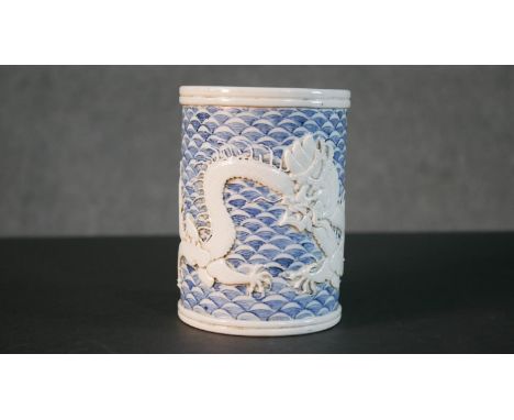 A 19th century relief dragon design porcelain brush pot with hand painted blue and white scale design ground. Impressed chara