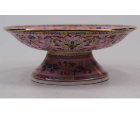 A Chinese porcelain pedestal dish, enamel decorated with crocus flowers on a pink ground, bearing six character mark to the u