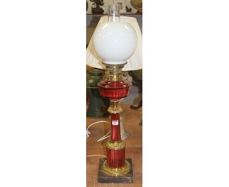 A Victorian style oil lamp, having an opalescent globular shade above a cranberry glass font with Hinks burner, on further cr