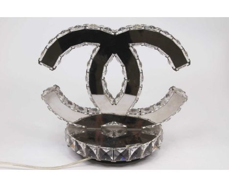 A modern Coco Chanel style table lamp of mirrored construction in the form of two entwined 'C's on circular base, height 25cm