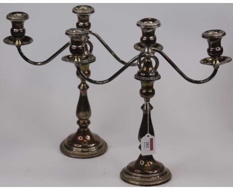 A pair of weighted American silver three-branch table candelabra, having scrolling arms upon a baluster column and circular b