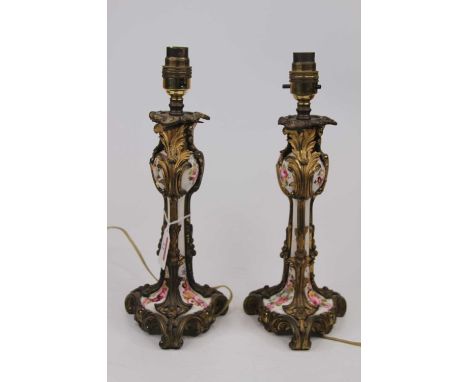 A pair of 19th century porcelain candlesticks, each hand painted with flowers and having gilt metal acanthus and leaf scrolli