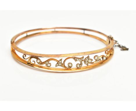 AN EDWARDIAN SEED PEARL BANGLE, hinged openwork floral design set with seed and split pearls, fitted with a push pin integrat