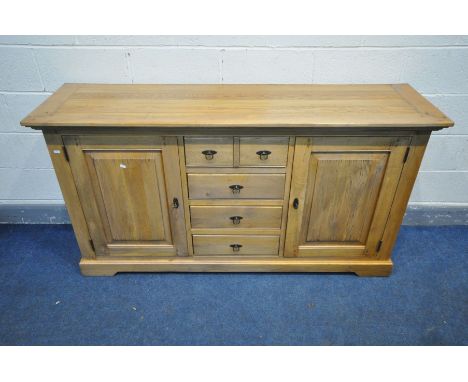 A SOLID GOLDEN OAK SIDEBOARD, a bank of four long drawers flanked by two cupboard doors enclosing a fixed shelf. width 170cm 