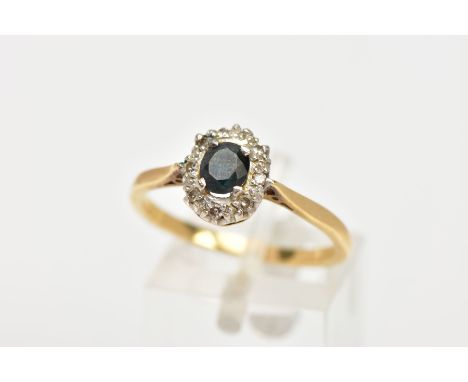 AN 18CT GOLD SAPPHIRE AND DIAMOND CLUSTER RING, centring on a four claw set, oval cut blue sapphire, within a surround of sin
