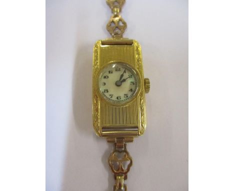 An 18ct gold ladies wristwatch with engine turned decoration and rectangular case, on a gold plated strap 