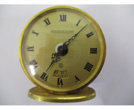A Jaeger Le Coultre miniature eight day travel alarm clock, having a 45mm gilt case, gilt dial with alarm aperture and Roman 