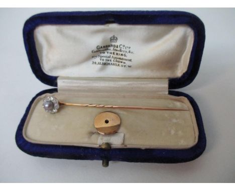 A gold coloured stick pin, the detachable top set with a central pearl surrounded by nine diamonds, with a stud clasp in a Ga