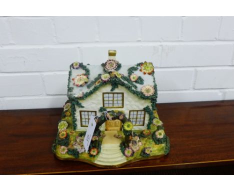 A large Staffordshire porcelain pastille burner modelled as a cottage, with floral encrusted roof on a rectangular stand mode