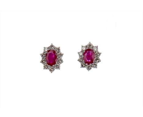 PAIR OF RUBY AND DIAMOND EARRINGS, each set with an oval ruby within a halo of round brilliant cut diamonds, the diamonds tot