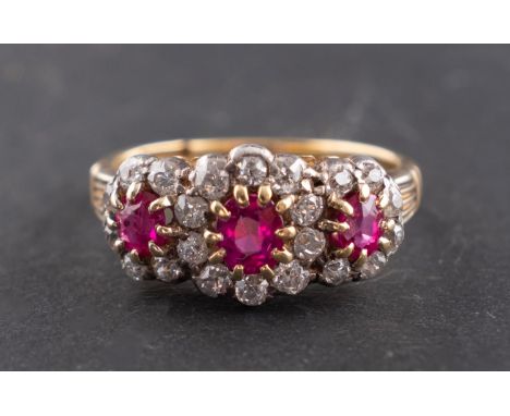 An oval, mixed-cut ruby and diamond, triple cluster ring, total estimated diamond weight ca. 0.40cts, stamped '18', length of