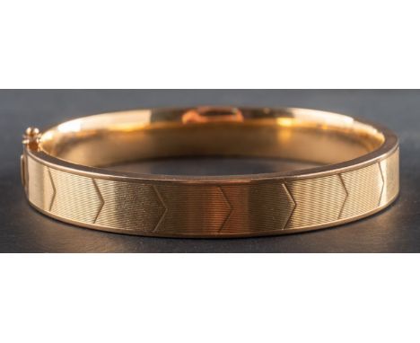 A hinged bangle, decorated with chevron pattern, stamped '750', inner diameter ca. 6cm, total weight ca. 25.7gms.