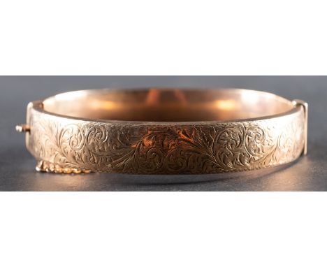 A 9ct gold hinged bangle, with foliate engraving, inner diameter ca. 6cm, total weight ca. 16gms.