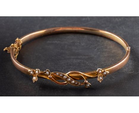 A hinged bangle, with floral spray motif as frontispiece, set with seed pearls, stamped '9CT', inner diameter ca. 6cm, total 